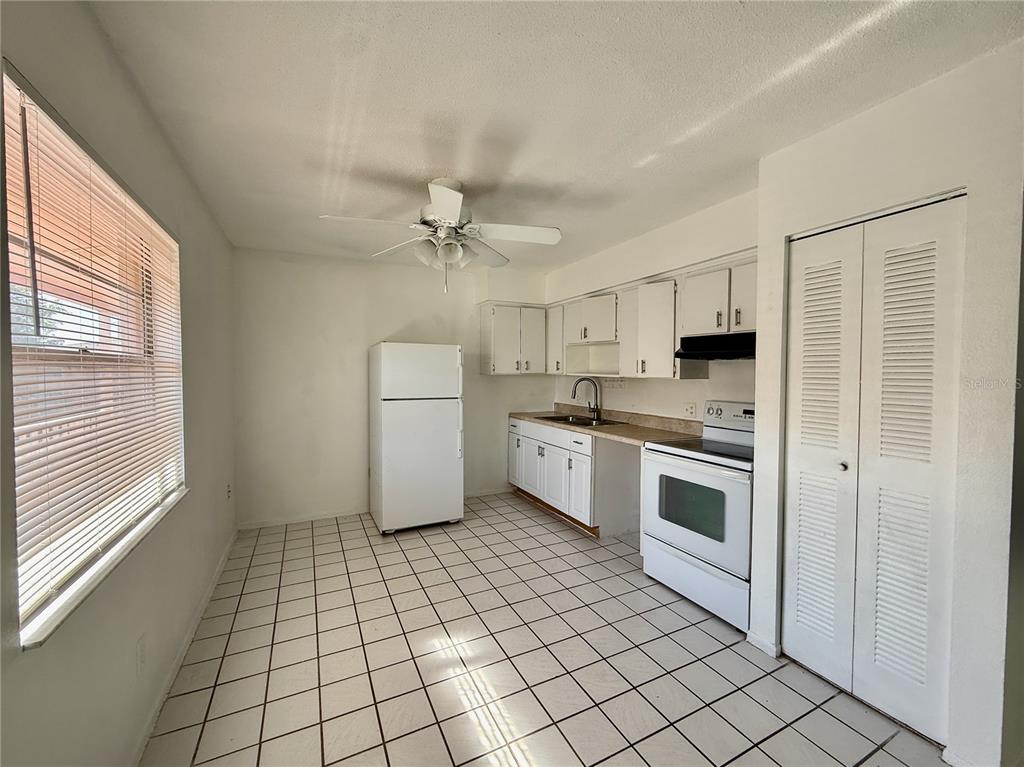 A kitchen with white cabinets, white appliances, and tiled flooring — 733 MICHIGAN COURT UNIT 4, ST CLOUD, FL