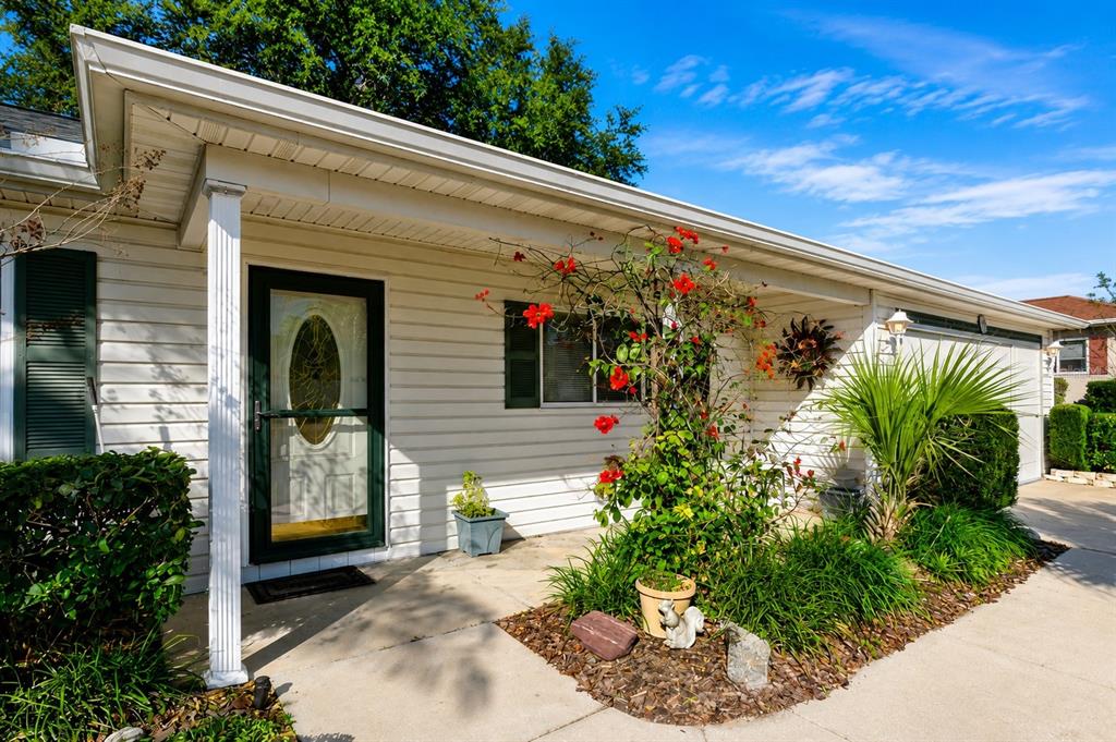 The exterior of a white house features a front door, a porch, and a garden bed — 13646 SE 91ST COURT, SUMMERFIELD, FL