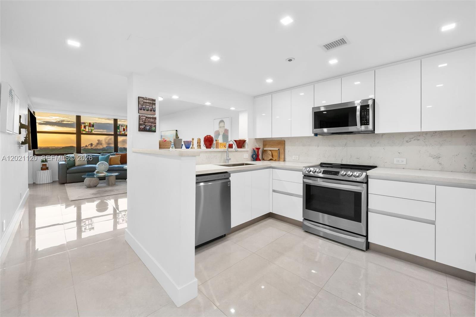 A modern kitchen with white cabinetry, stainless steel appliances, and a view of the sunset — 2555 Collins Ave # 1106, Miami Beach FL 33140, MIAMI BEACH, FL