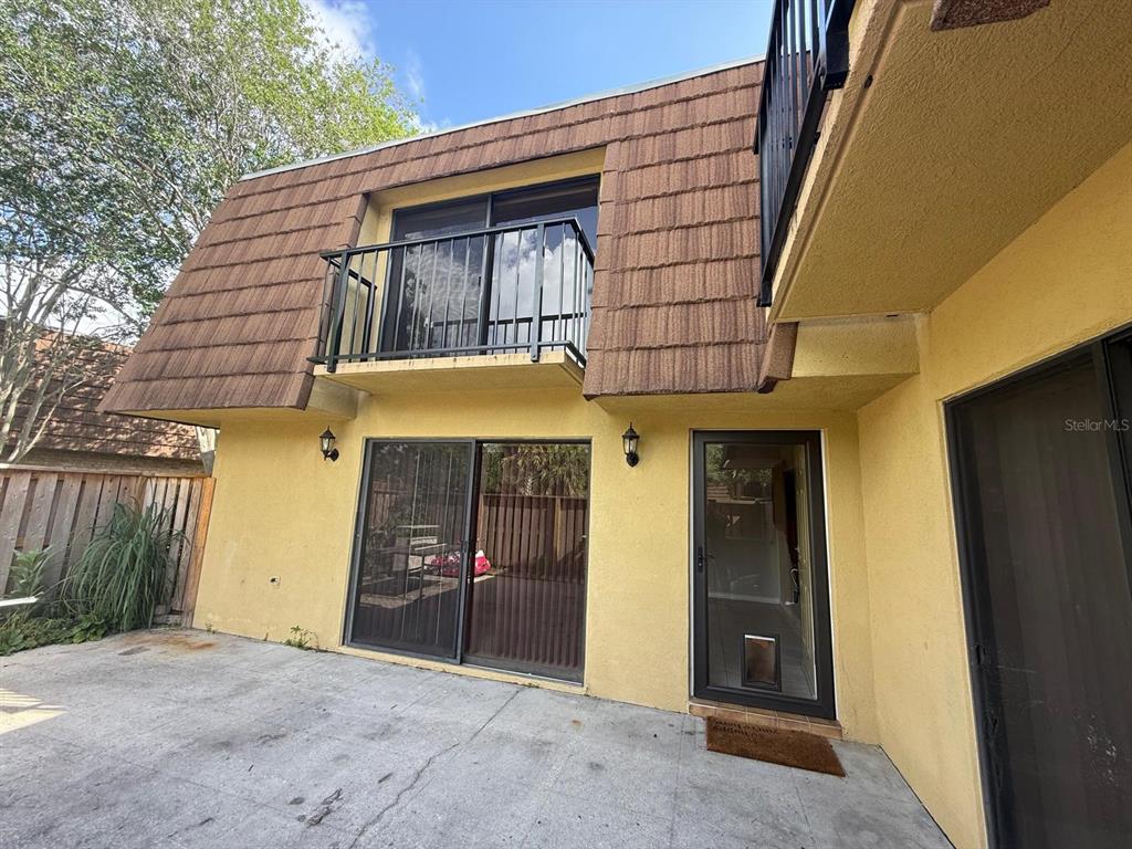 A two-story building exterior features a concrete patio, sliding glass doors, and a small balcony — 5296 CYPRESS COURT UNIT 433, ORLANDO, FL