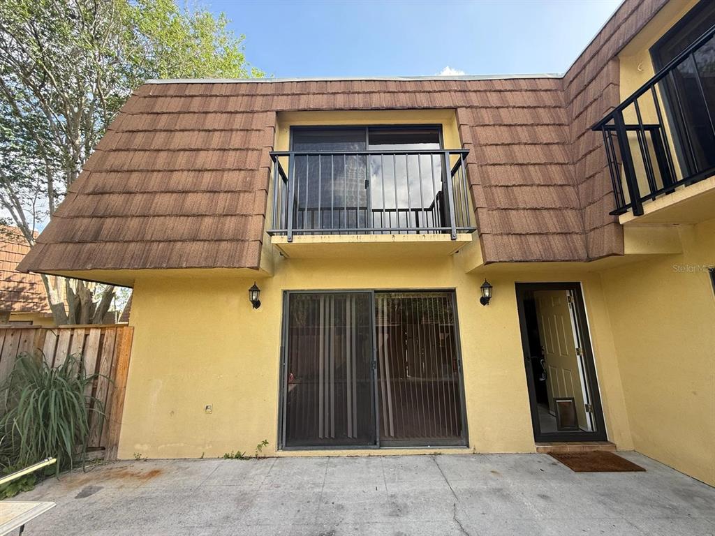 The exterior of a two-story yellow building features a balcony, sliding doors, and brown shingles — 5296 CYPRESS COURT UNIT 433, ORLANDO, FL
