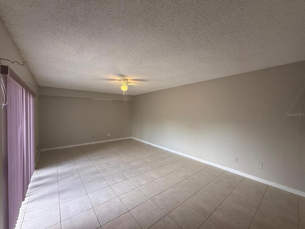 An empty room with beige walls, tile flooring, and a ceiling fan — 5296 CYPRESS COURT UNIT 433, ORLANDO, FL