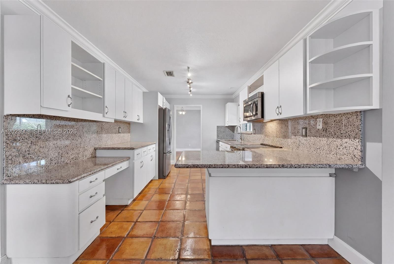 A kitchen features white cabinets, granite countertops, and terracotta tile flooring — 14001 SW 108th St, Miami FL 33186, MIAMI, FL