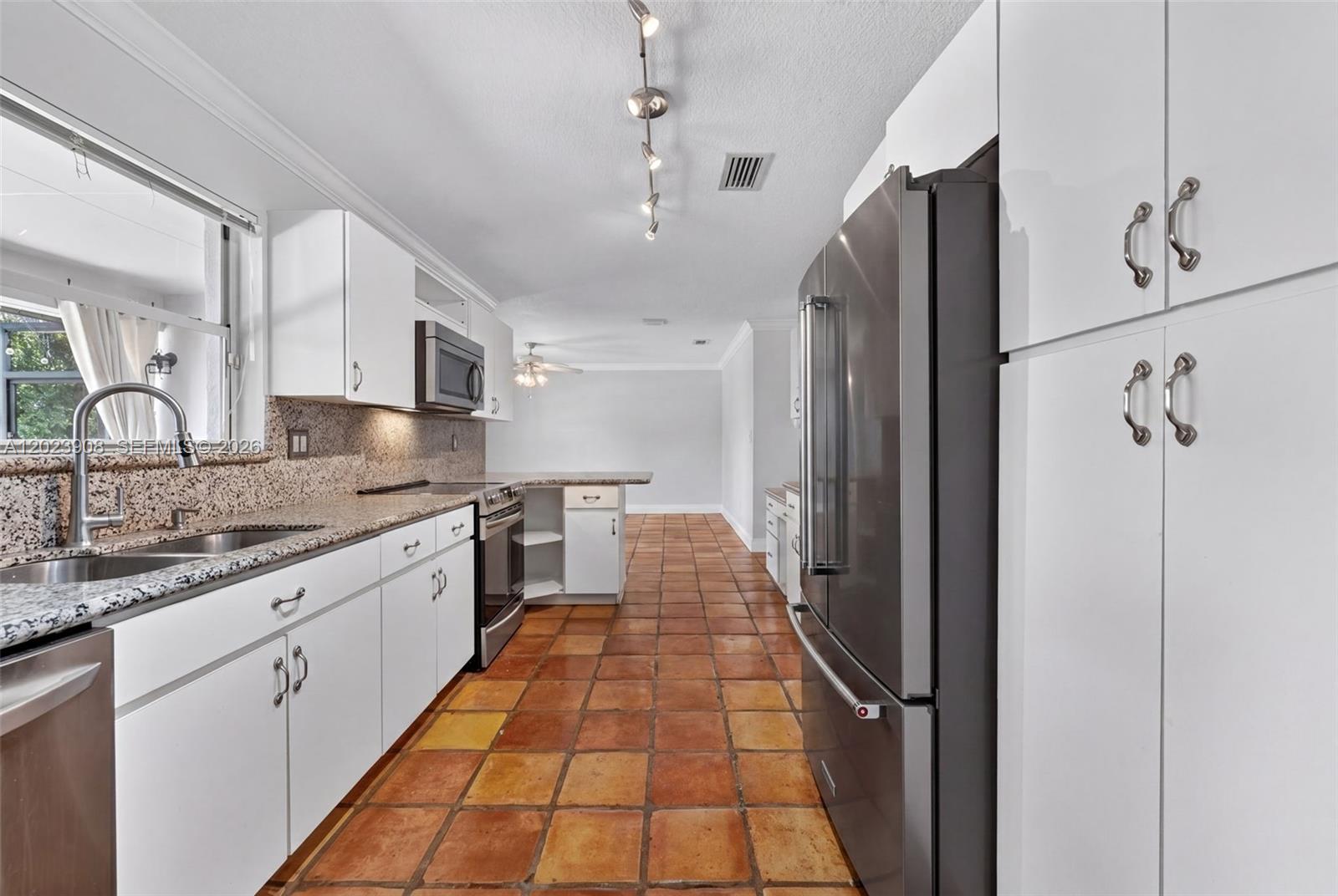 A kitchen features white cabinets, granite countertops, stainless steel appliances, and terracotta tile flooring — 14001 SW 108th St, Miami FL 33186, MIAMI, FL