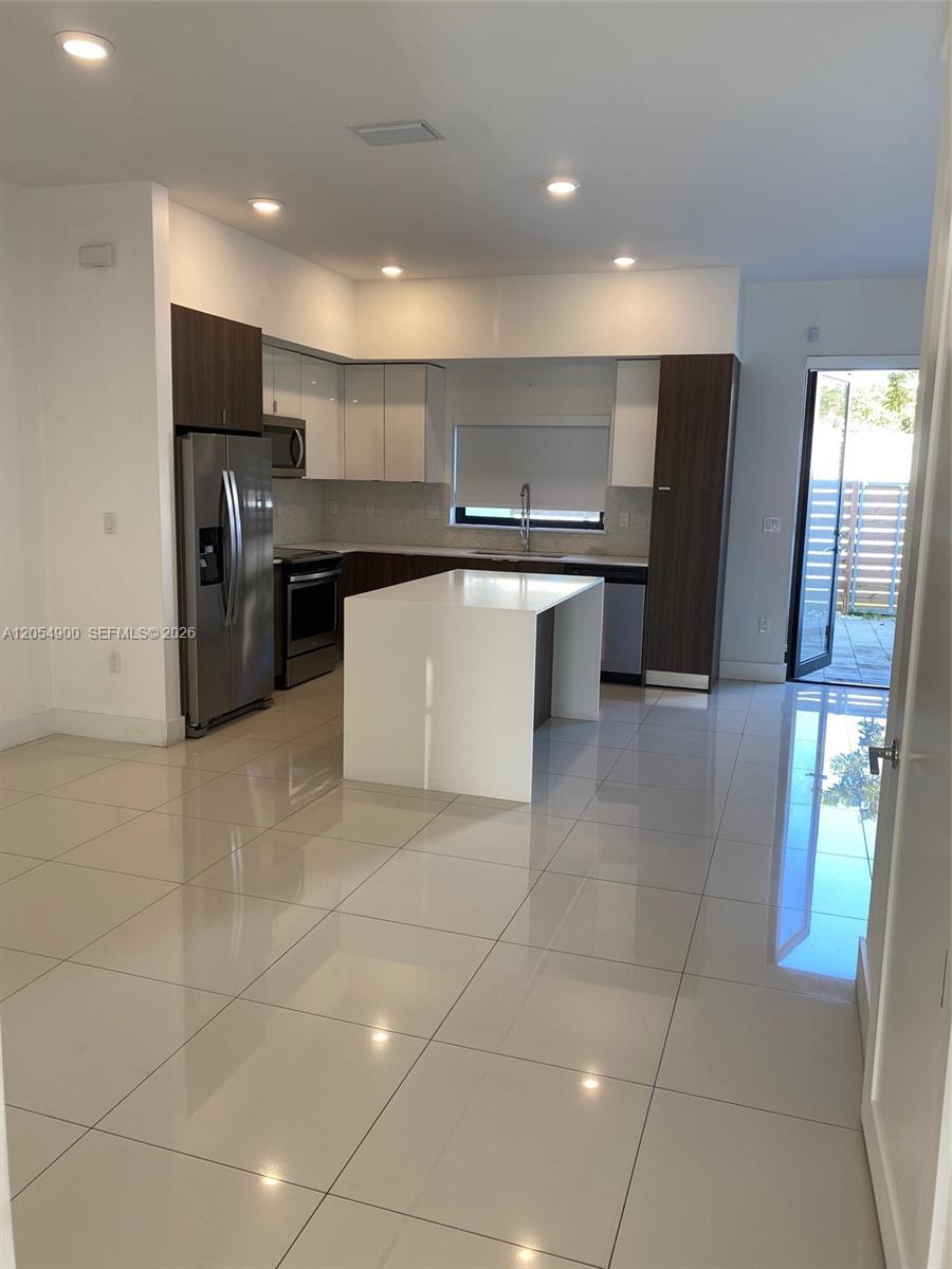 A modern kitchen features white cabinets, dark wood accents, a central island, and tile flooring — 10602 SW 118th Ave # 10602, Miami FL 33186, MIAMI, FL