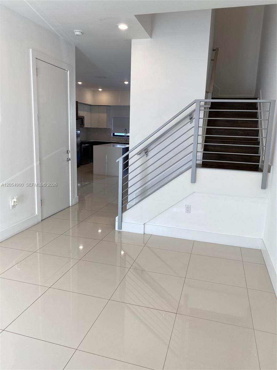 A tiled entryway features a white door, a modern metal staircase railing, and a kitchen — 10602 SW 118th Ave # 10602, Miami FL 33186, MIAMI, FL
