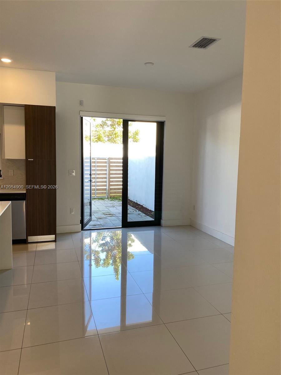A modern room features white tile floors, a kitchen cabinet unit, and a sliding glass door — 10602 SW 118th Ave # 10602, Miami FL 33186, MIAMI, FL