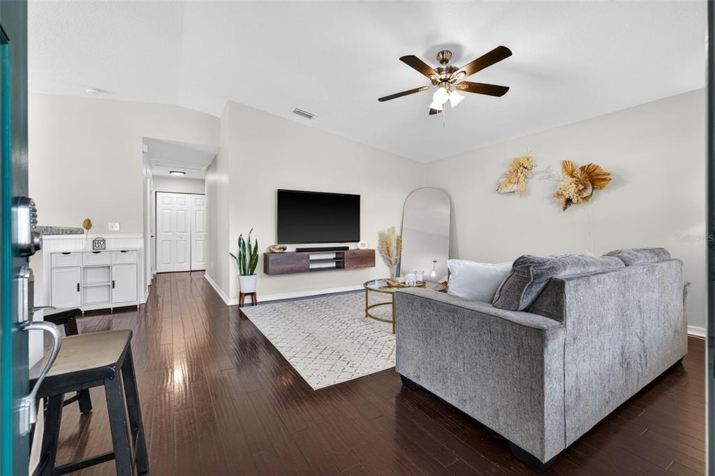 A living room features dark hardwood floors, a gray sofa, a wall-mounted TV, and a rug — 5801 N MIAMI PLACE, TAMPA, FL