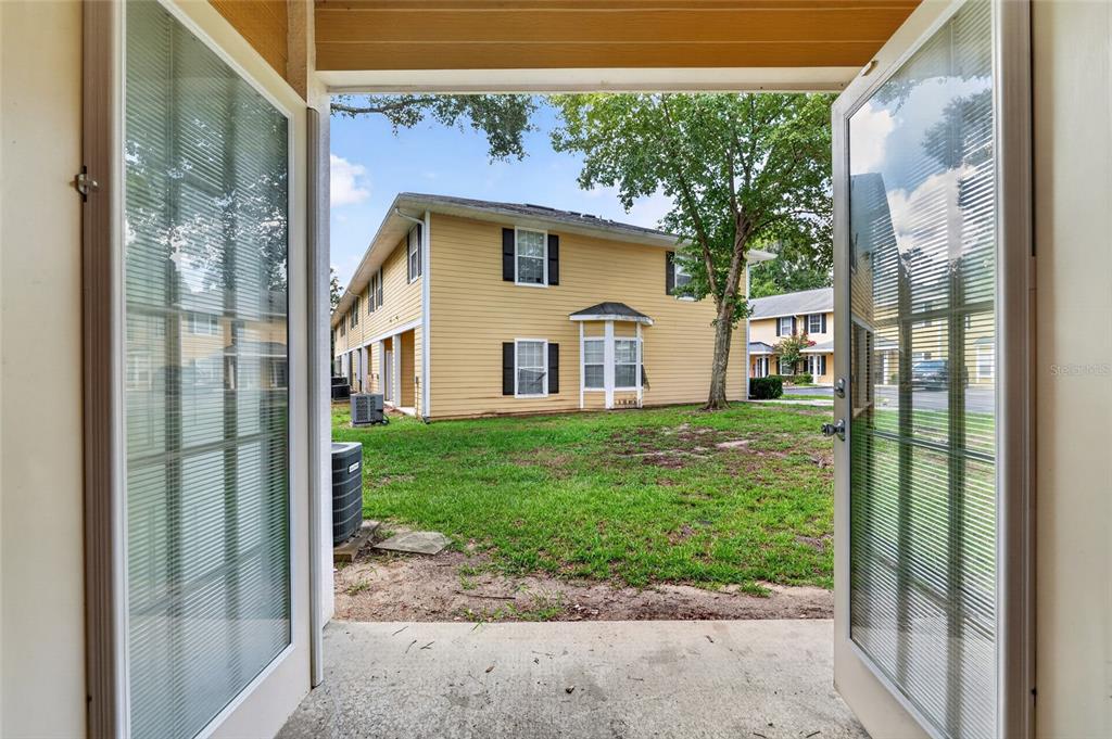 View from an open doorway looking out at a grassy yard and yellow apartment buildings — 2927 SW 35TH PLACE UNIT 115, GAINESVILLE, FL