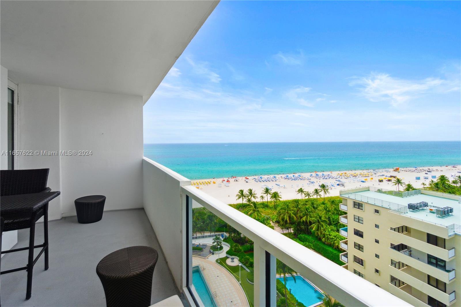 A balcony with outdoor furniture overlooks a beach, ocean, and a swimming pool — 100 Lincoln Rd # 1534, Miami Beach FL 33139, MIAMI BEACH, FL