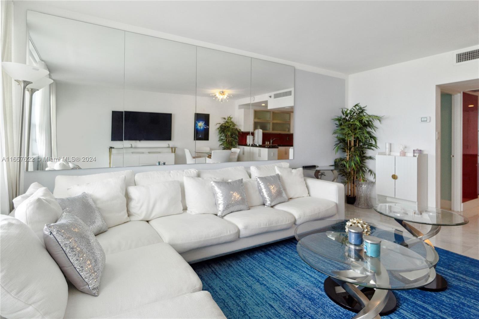A living room features a large white sectional sofa, a blue rug, and mirrored walls — 100 Lincoln Rd # 1534, Miami Beach FL 33139, MIAMI BEACH, FL