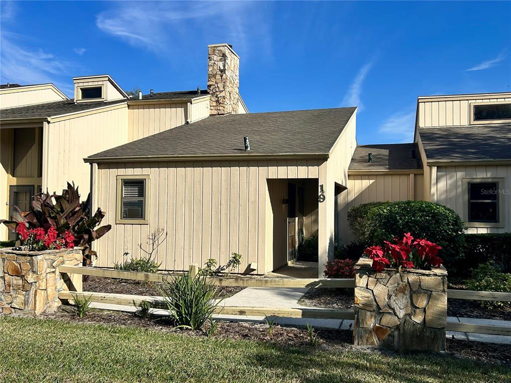 A tan, single-story townhouse with a stone chimney and stone-faced planters in the front yard — 19 ASPEN DR. UNIT 19, HAINES CITY, FL