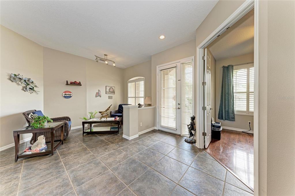 A tiled entryway leads into a living area with wicker furniture and a glass door — 10918 BULLRUSH TERRACE, LAKEWOOD RANCH, FL
