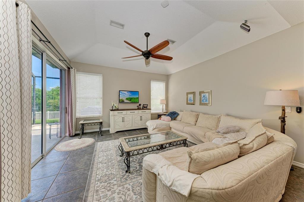 A living room features a large sectional sofa, a coffee table, and sliding glass doors — 10918 BULLRUSH TERRACE, LAKEWOOD RANCH, FL
