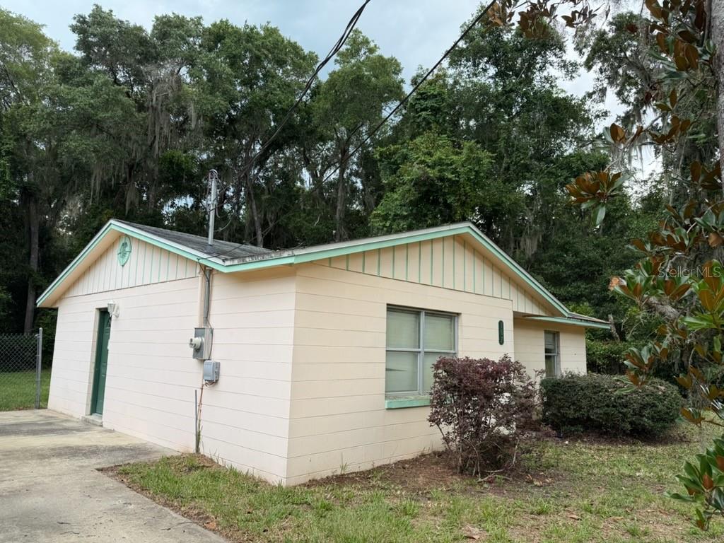 The exterior of a light-colored, single-story house with a gable roof and a concrete driveway — 107 WOODLAWN ROAD, SATSUMA, FL