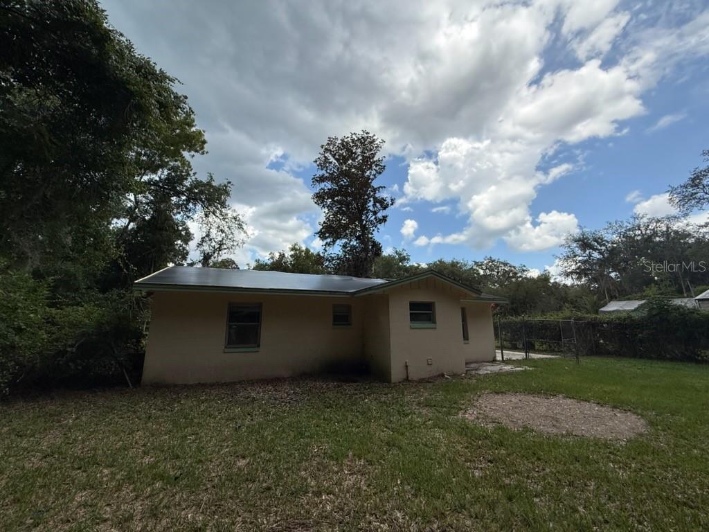 The exterior view shows the back of a single-story house with a metal roof — 107 WOODLAWN ROAD, SATSUMA, FL