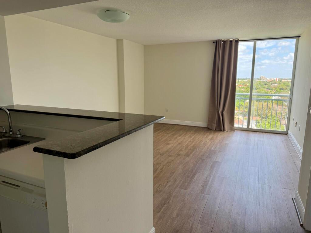 An open-concept kitchen with a breakfast bar overlooks a living area with wood-look flooring — 3000 Coral Way # 1007, Miami FL 33145, MIAMI, FL