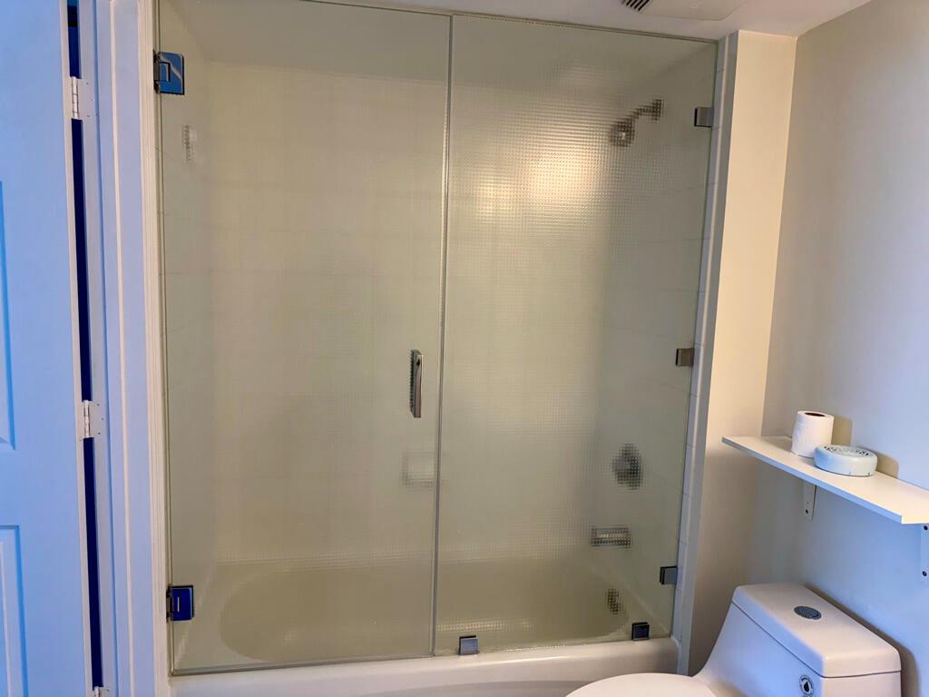A bathroom features a glass-enclosed shower with textured panels and a white toilet nearby — 3000 Coral Way # 1007, Miami FL 33145, MIAMI, FL