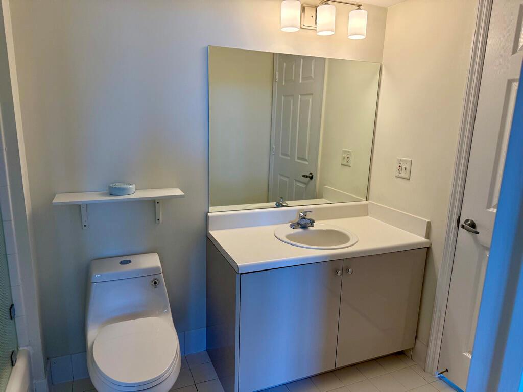A bathroom features a vanity with a white countertop, a mirror, and a toilet — 3000 Coral Way # 1007, Miami FL 33145, MIAMI, FL