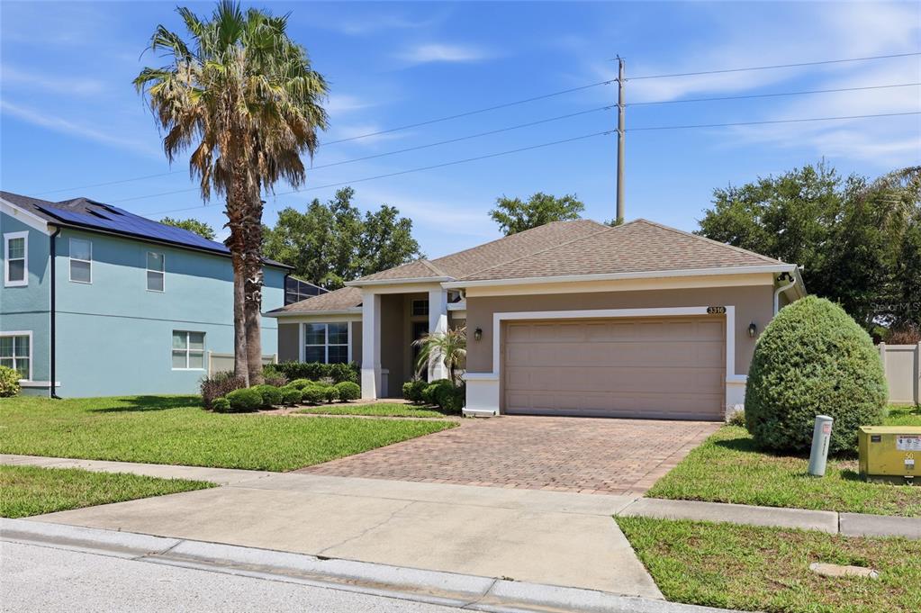 A single-story house with a tan stucco exterior, a paved driveway, and a palm tree — 3316 MCCORMICK WOODS DRIVE, OCOEE, FL