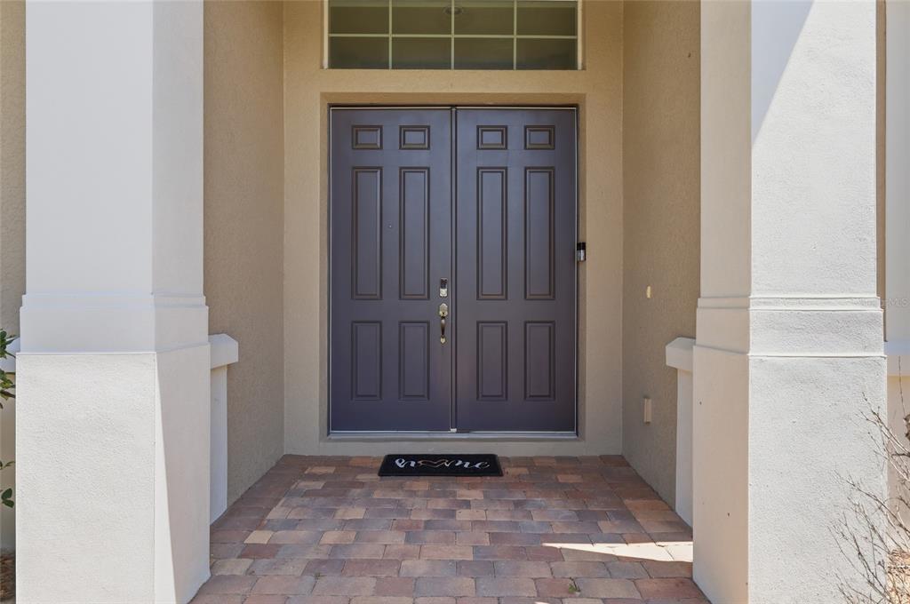 A pair of dark brown double doors with a transom window sits under a covered entryway — 3316 MCCORMICK WOODS DRIVE, OCOEE, FL