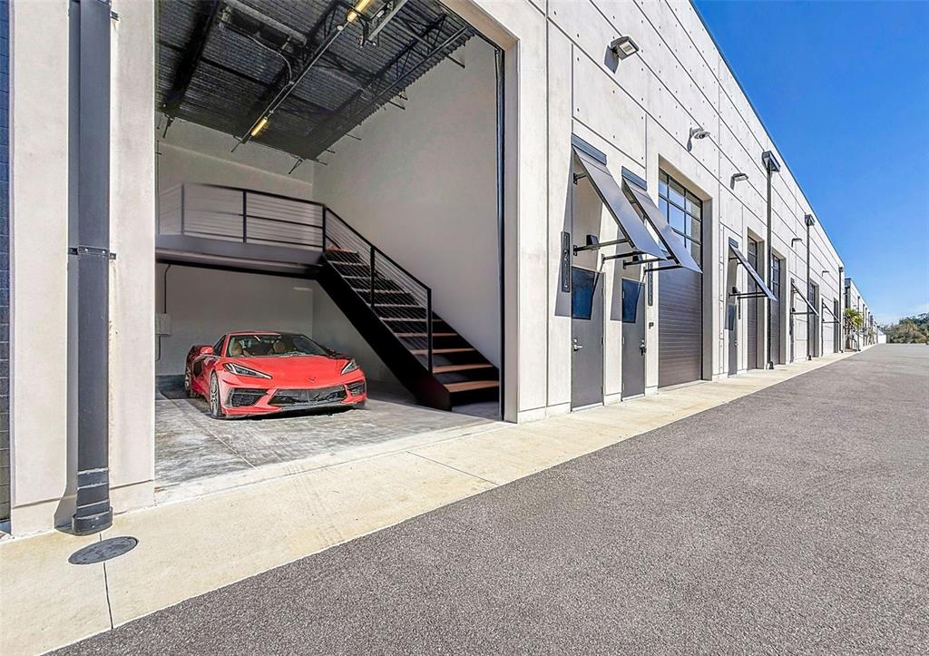 A red sports car is parked inside a modern industrial garage with a metal staircase — 6500 MOTOR ENCLAVE WAY UNIT 1214, TAMPA, FL