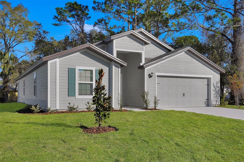 A single-story house with light gray siding, a two-car garage, and a green lawn — 48 PRATTWOOD LANE, PALM COAST, FL