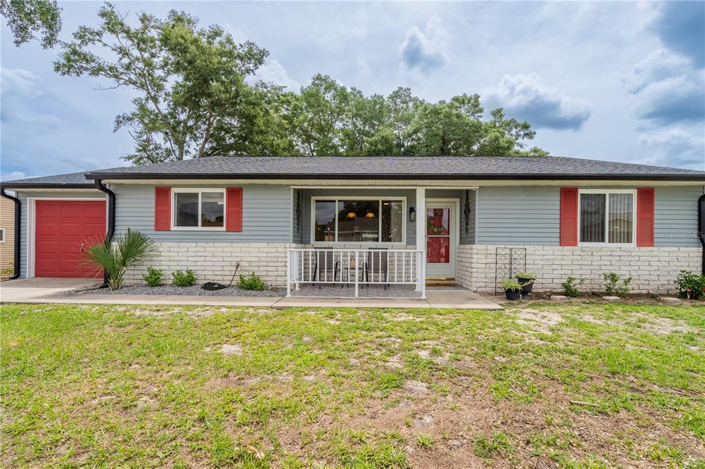 A single-story house with gray siding, white brick, red shutters, and a front porch — 10839 SW 87TH TERRACE, OCALA, FL