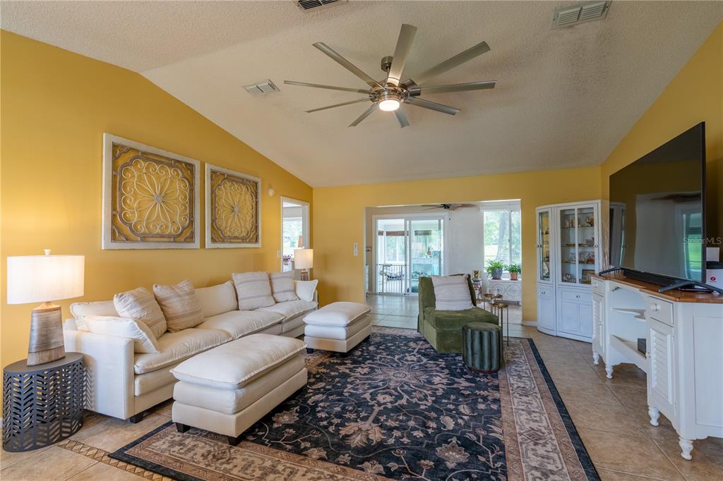 A living room features yellow walls, a large area rug, white furniture, and a television — 10839 SW 87TH TERRACE, OCALA, FL