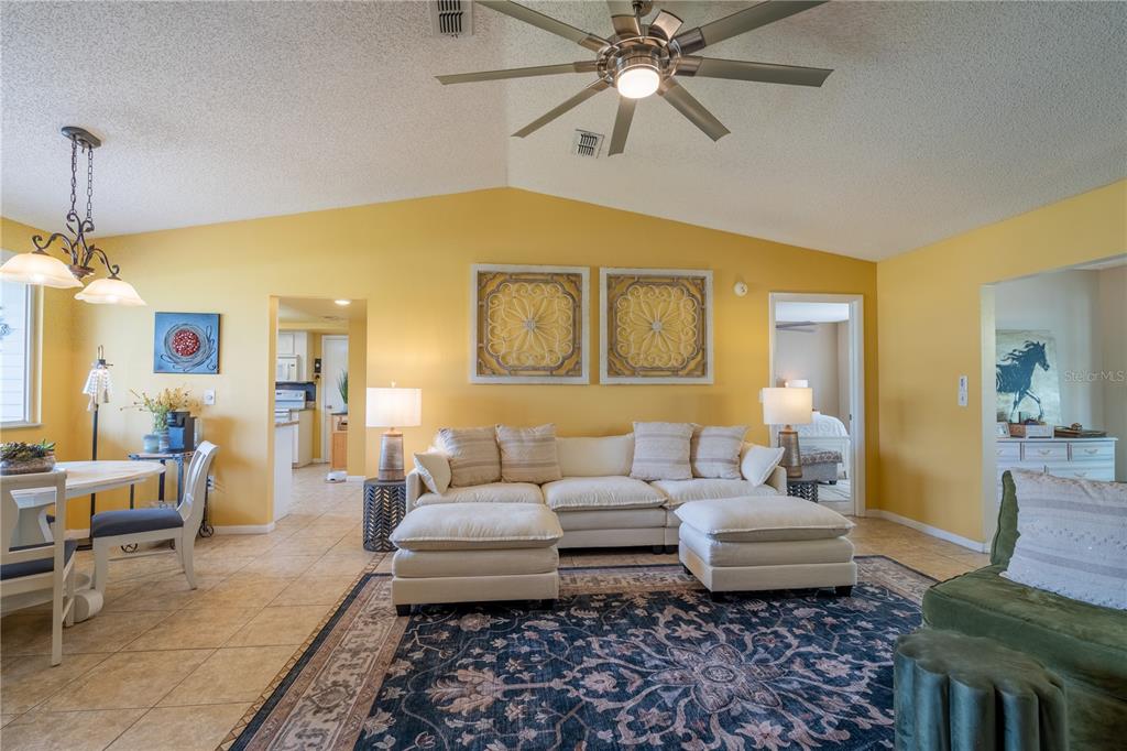 A living room with yellow walls, a vaulted ceiling, and a large white sectional sofa — 10839 SW 87TH TERRACE, OCALA, FL