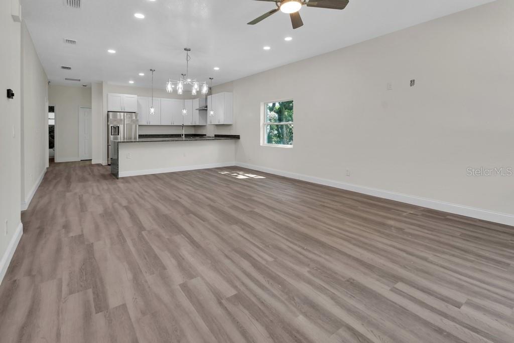 An open-concept living area features light wood-look flooring, recessed lighting, and a kitchen with white cabinetry — 556 WALLACE STREET, DAYTONA BEACH, FL