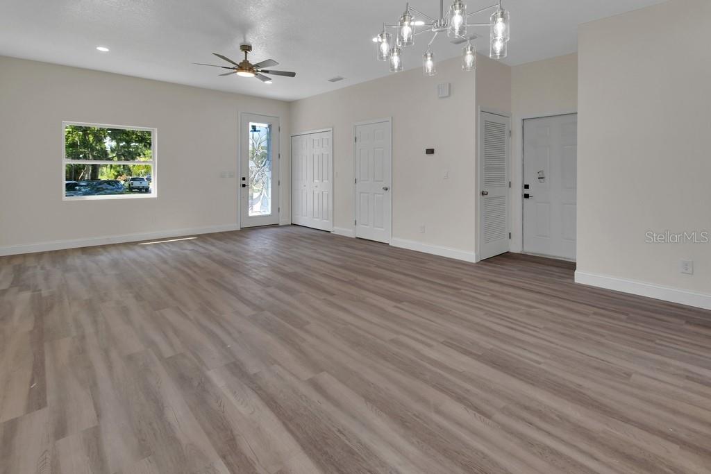 A spacious room features light wood-look flooring, a ceiling fan, and a modern chandelier — 556 WALLACE STREET, DAYTONA BEACH, FL