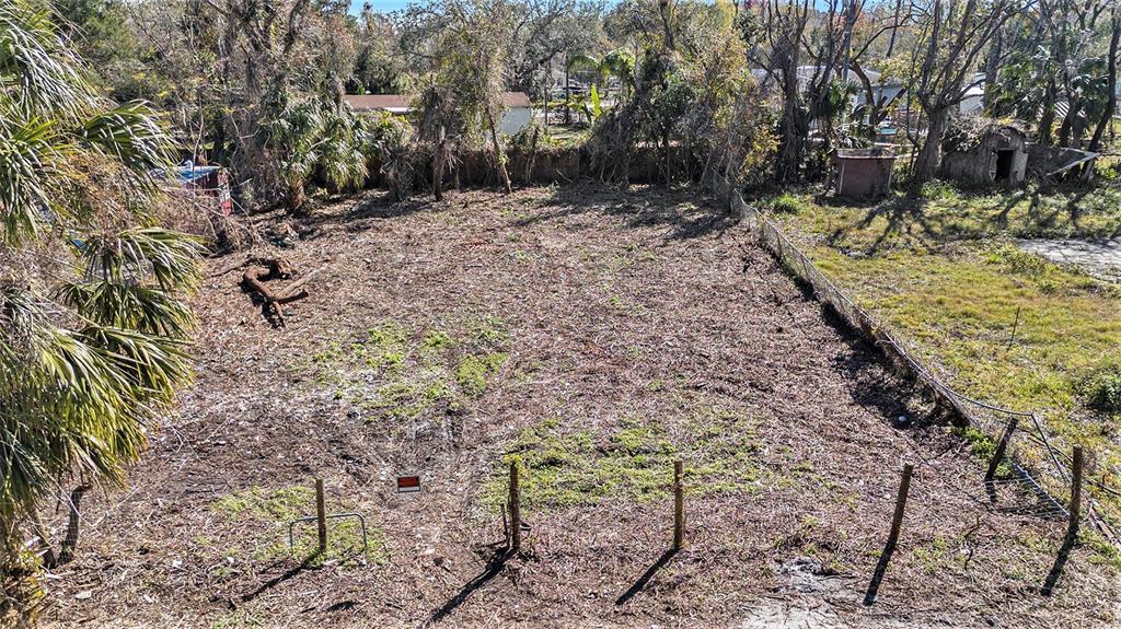 An elevated view of a cleared, fenced-in vacant lot with scattered vegetation and trees — POLO STREET, NEW PORT RICHEY, FL