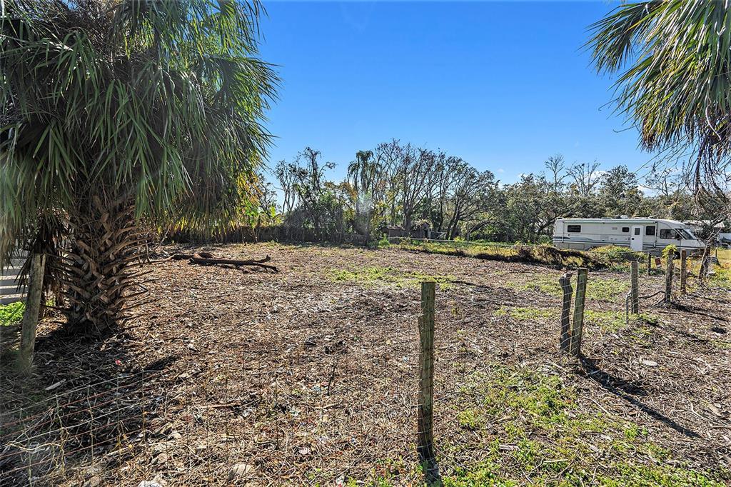 A fenced, cleared vacant lot features a large palm tree and a parked recreational vehicle — POLO STREET, NEW PORT RICHEY, FL