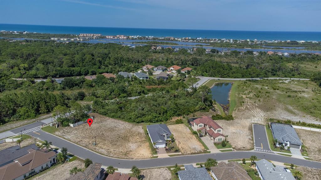 An aerial view shows a vacant residential lot marked with a pin in a coastal neighborhood — 2 RIO VISTA DRIVE, PALM COAST, FL