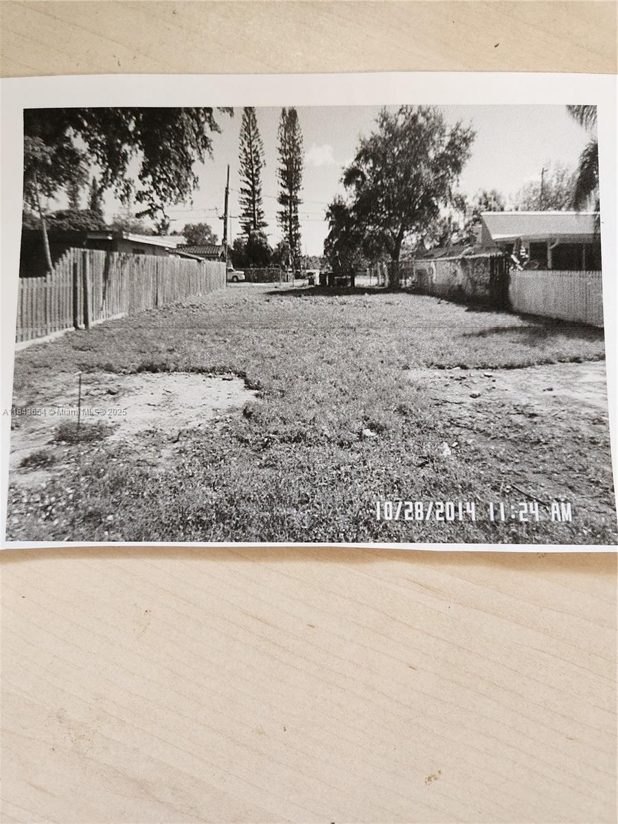 A vacant, grassy residential lot is enclosed by wooden fences on both sides — 315 N 61st Ave, Hollywood FL 33024, HOLLYWOOD, FL