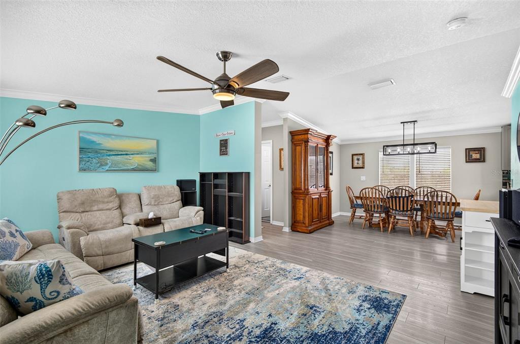 A living room with a teal accent wall, beige sofas, and an adjacent dining area — 6806 SEA RANCH DRIVE, HUDSON, FL