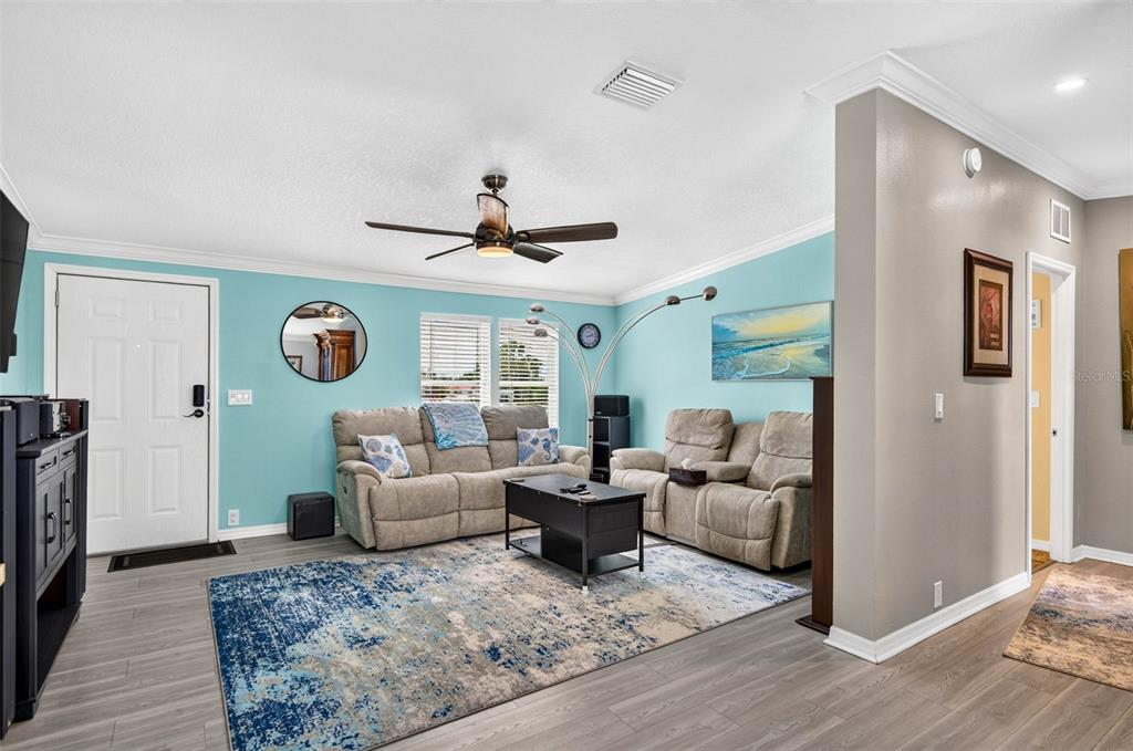 A living room features light blue walls, gray wood-look flooring, two beige sofas, and a rug — 6806 SEA RANCH DRIVE, HUDSON, FL