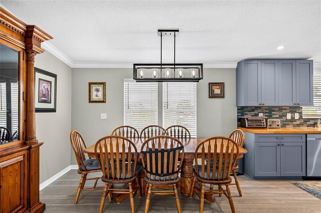 A dining area features a wooden table, spindle chairs, a modern light fixture, and blue cabinets — 6806 SEA RANCH DRIVE, HUDSON, FL