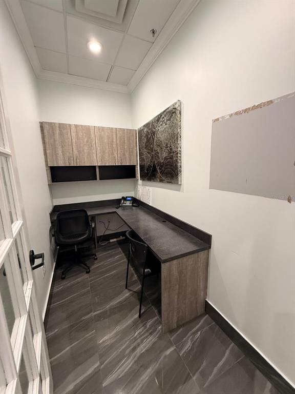 A small office features a built-in desk, upper cabinets, a world map, and tiled flooring — 7901 KINGSPOINTE PARKWAY UNIT 19 #Office 3, ORLANDO, FL