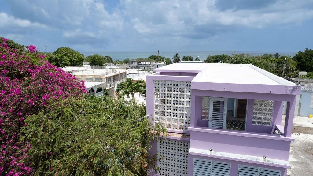 An elevated view of a purple two-story house with a white roof and ocean view — 393 CALLE JOSE SUEIRO, VIEQUES, PR