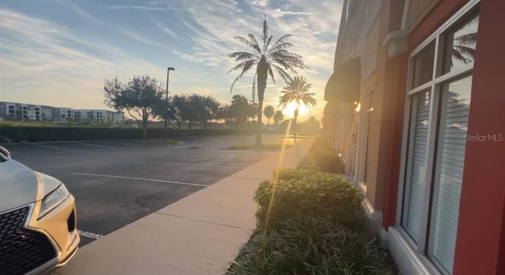 A parking lot and sidewalk are adjacent to a building exterior at sunset — 245 BELLAGIO CIRCLE, SANFORD, FL