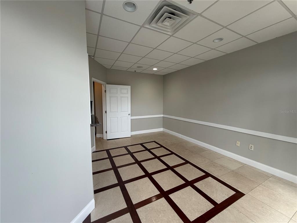A room with a drop ceiling, tile flooring with a grid pattern, and gray walls — 245 BELLAGIO CIRCLE, SANFORD, FL