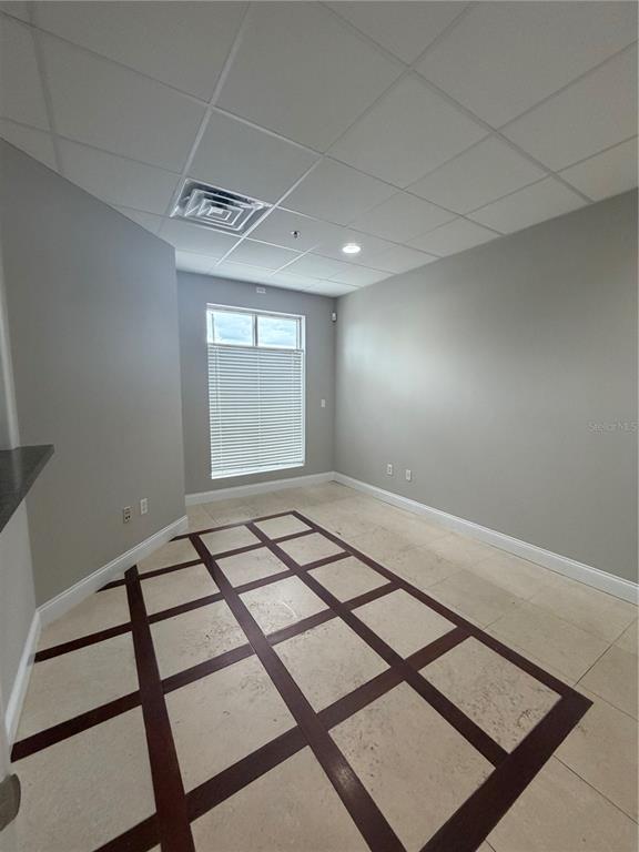 An empty office space features gray walls, a drop ceiling, and a tiled floor — 245 BELLAGIO CIRCLE, SANFORD, FL