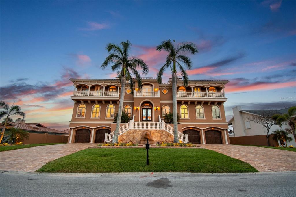 A three-story Mediterranean-style house with a stone staircase, arched windows, and two tall palm trees — 5810 MARINER STREET, TAMPA, FL