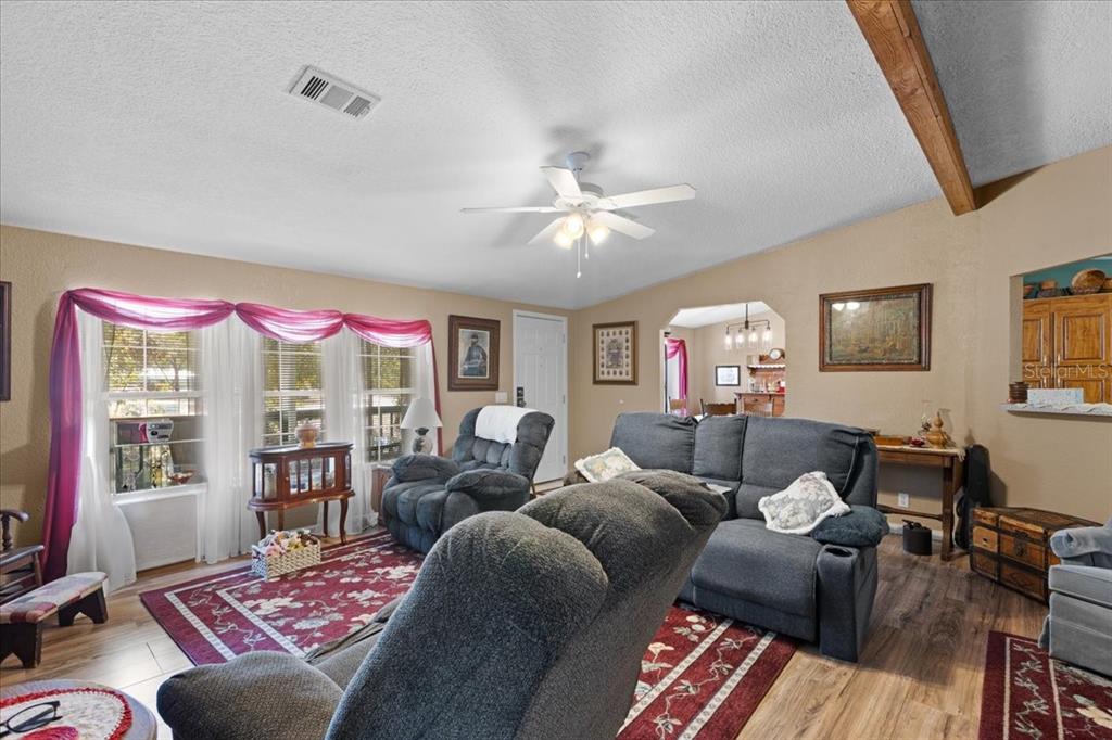 A living room features gray reclining furniture, a red patterned rug, and pink window swags — 1658 NE 743RD STREET, OLD TOWN, FL