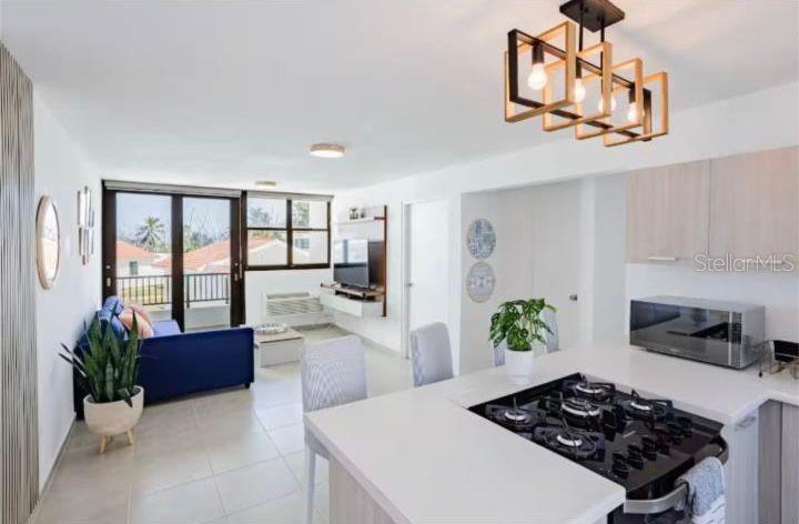 An open-concept living area features a kitchen island with a gas cooktop and modern lighting — C-214 MARBELA CASA DE PLAYA, ISABELA, PR