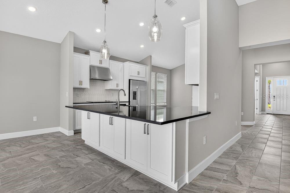 A kitchen with white cabinets, a black countertop island, and gray tile flooring — 39 OCONEE DRIVE, PALM COAST, FL