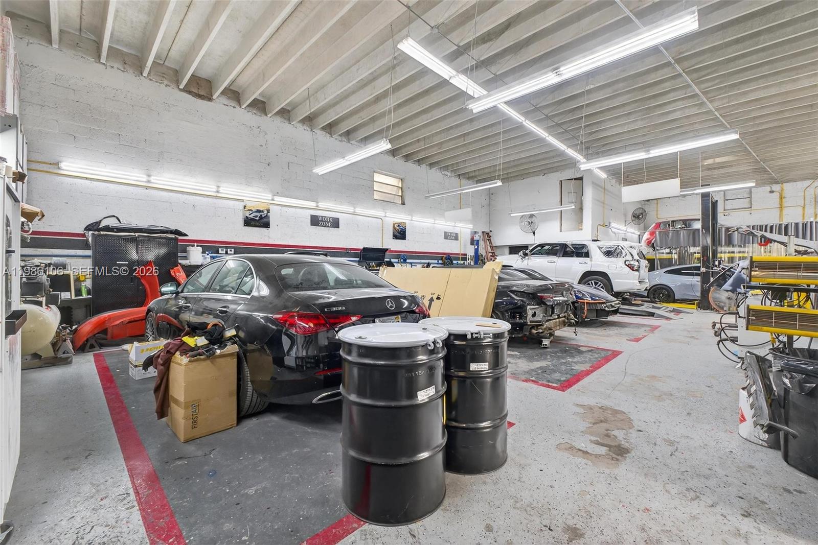 An auto repair shop features multiple vehicles, industrial lighting, and two large black storage drums — 0000 NW 56, Doral FL 33166, DORAL, FL