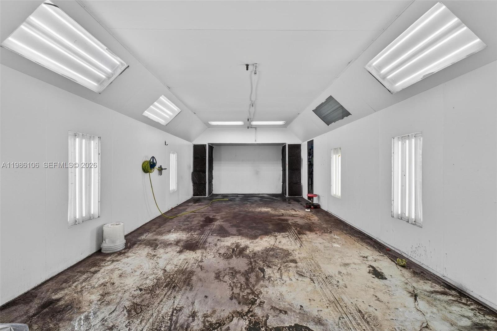 This is a paint spray booth with white walls, overhead lighting, and a stained concrete floor — 0000 NW 56, Doral FL 33166, DORAL, FL